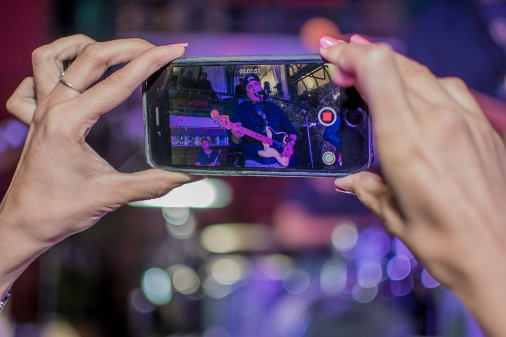 Invitée qui filme le concert avec son téléphone, sous les lumières