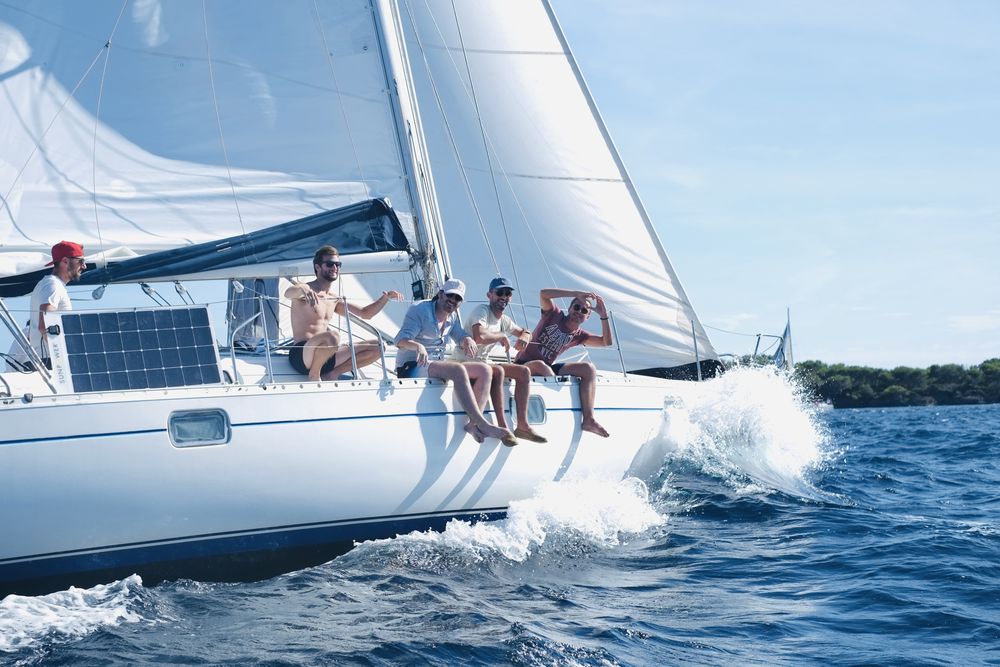 Équipiers assis au vent sur le bord d'un voilier lancé dans la vague