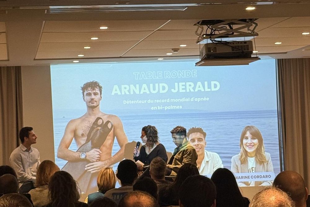 Table ronde sur scène devant un grand écran, la salle au premier plan