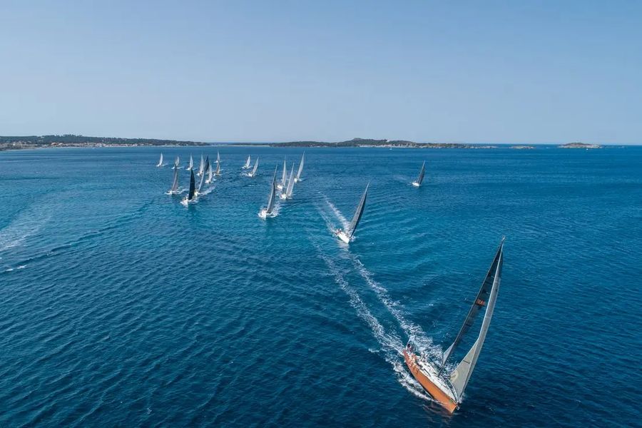 Voilier en tête et flotte au départ d'une régate