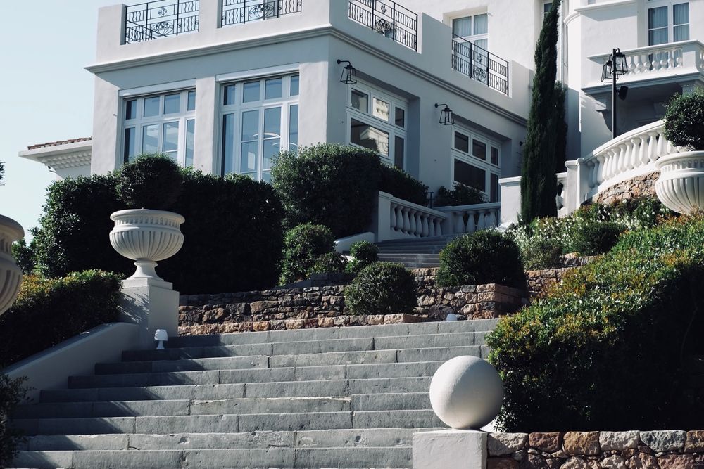 Escalier et façade d'une villa blanche entourée de jardins