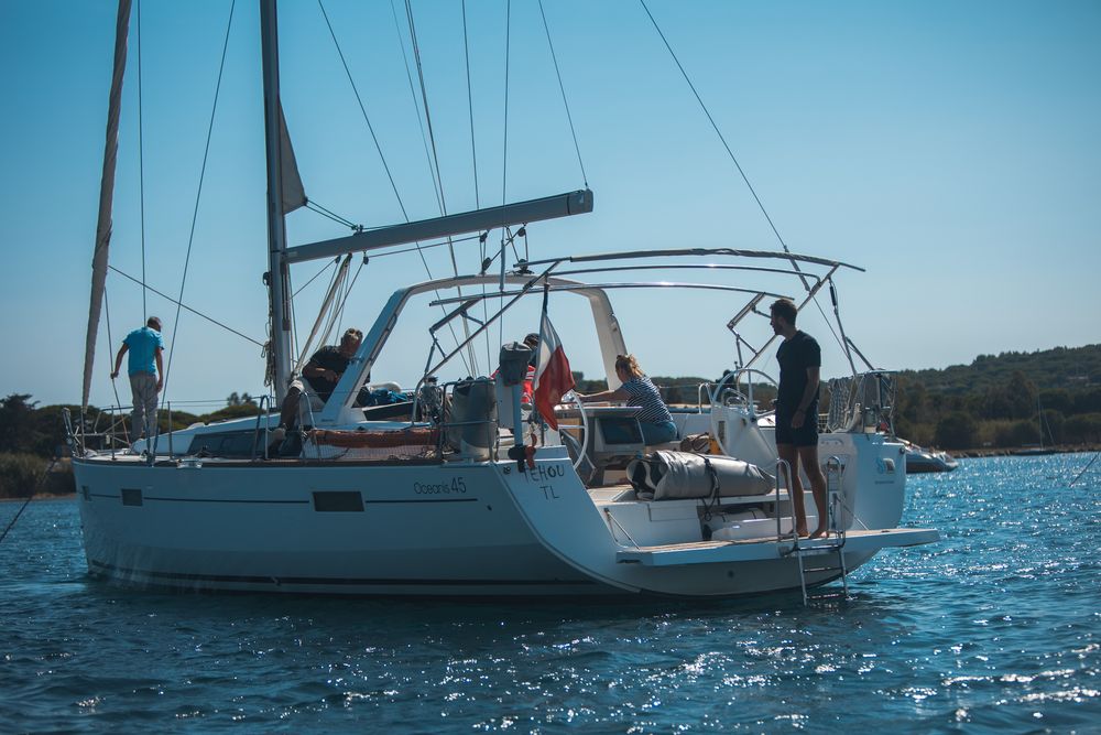 Voilier au mouillage dans une baie, l'équipe à bord