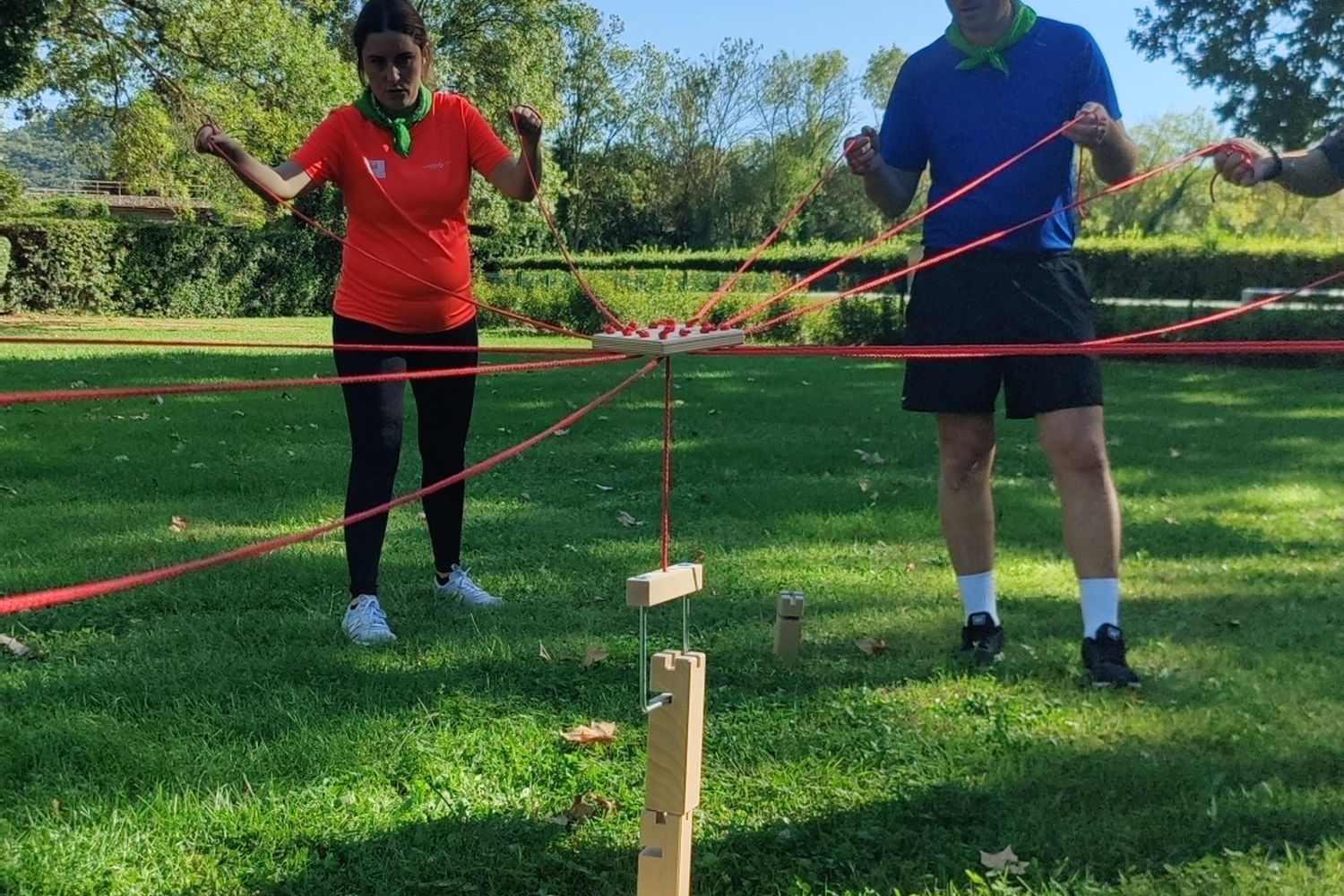 Épreuve des cordes dans un parc : chaque équipier tient un fil pour guider l'objet
