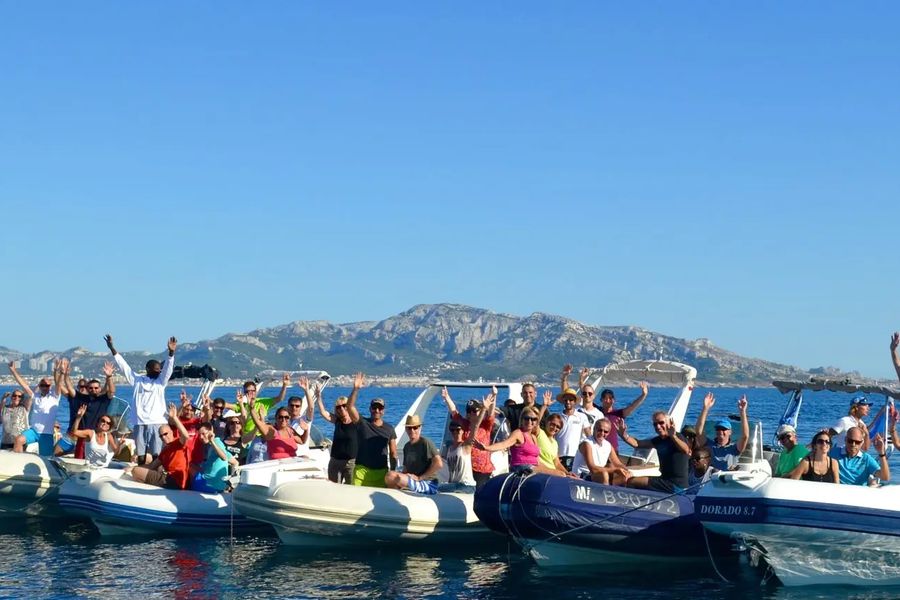 Équipes à bord de semi-rigides, bras levés, pendant un rallye nautique