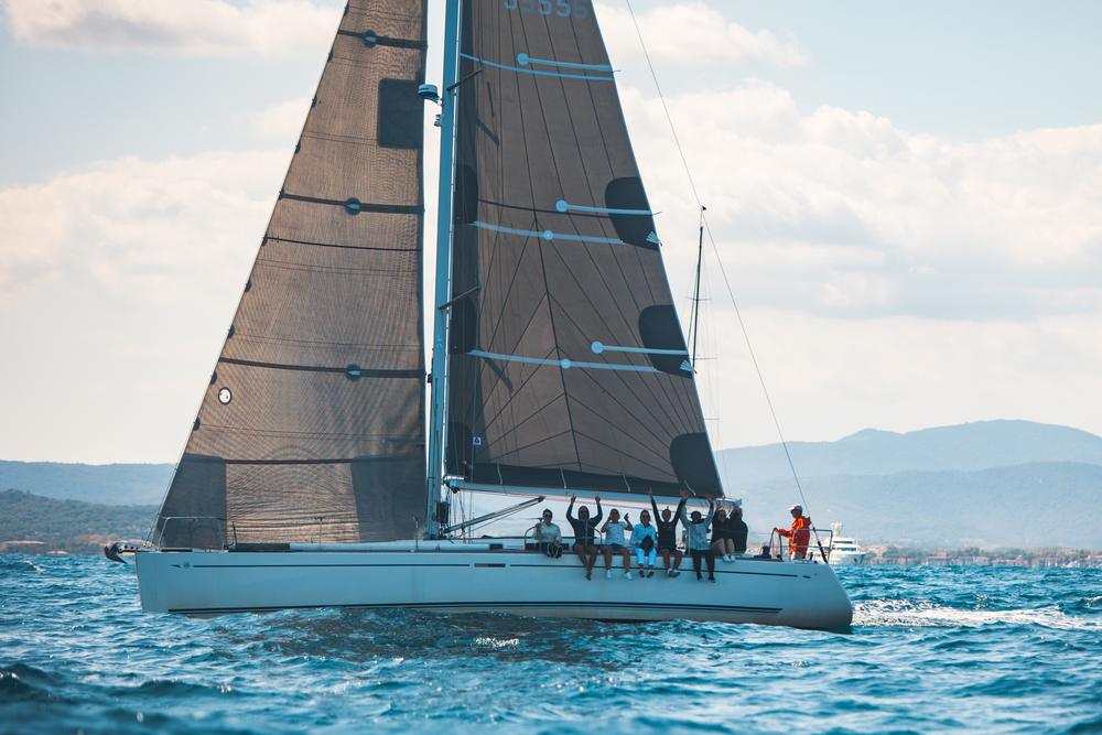 Voilier sous voiles sombres dans le golfe de Saint-Tropez, l'équipage au rappel