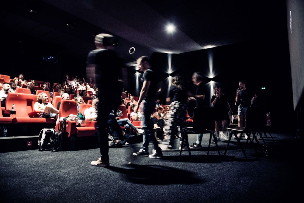 Intervenants rejoignant la scène devant une salle aux fauteuils rouges