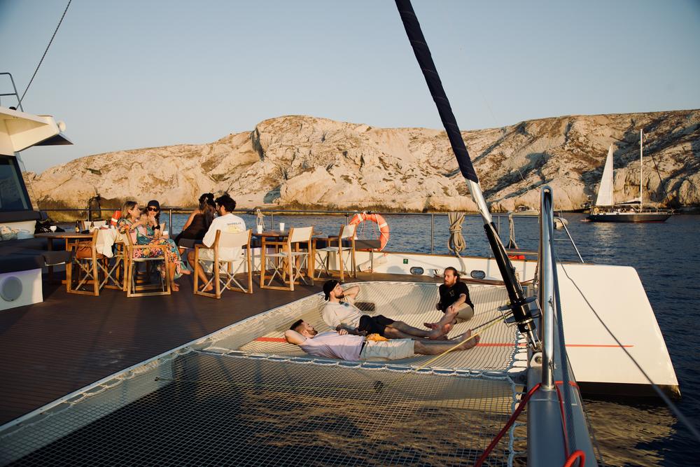 Pont d'un catamaran au coucher du soleil face aux falaises des Calanques