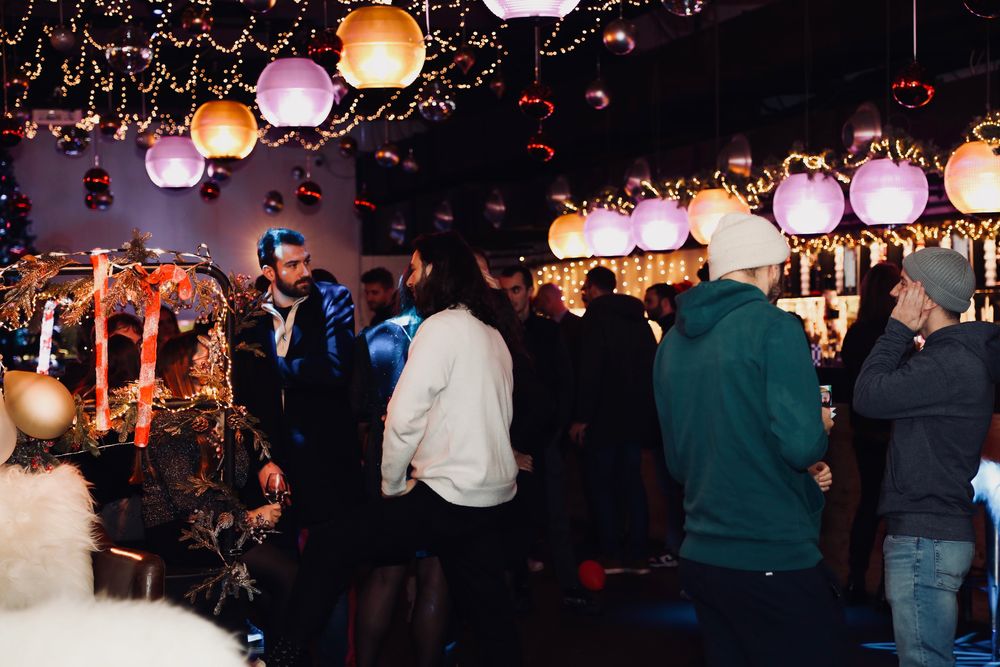 Salle décorée de lanternes et de guirlandes, pleine d'invités autour du bar