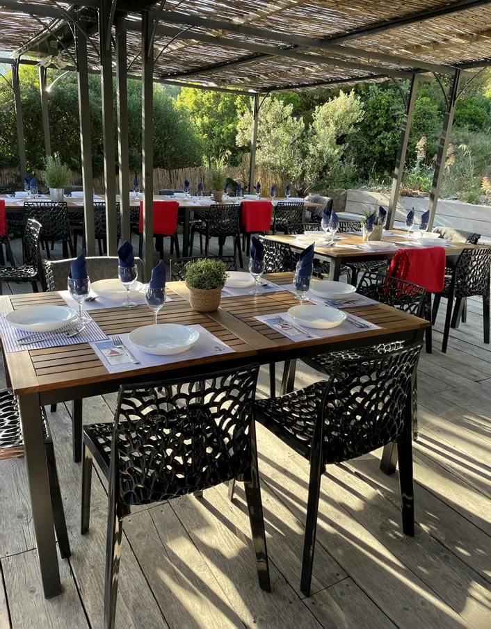 Les tables dressées sous la pergola, face à la calanque