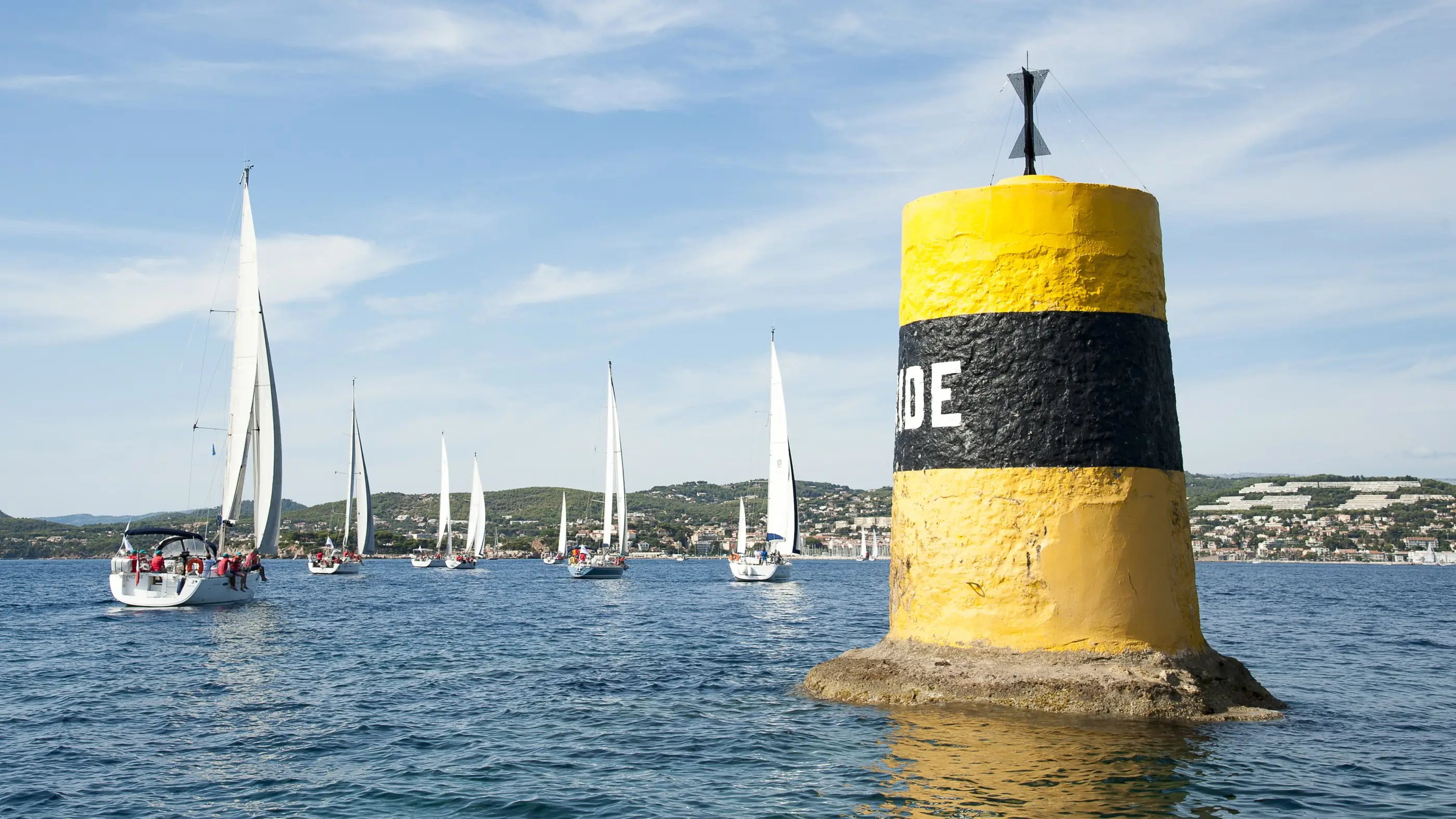 La flotte d'une régate d'entreprise au passage de la balise, devant la côte