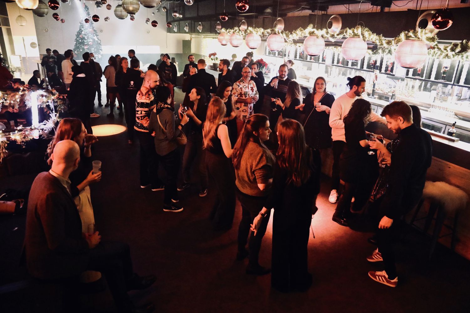 Salle privatisée pleine de monde pendant une soirée de fin d'année, sous les guirlandes