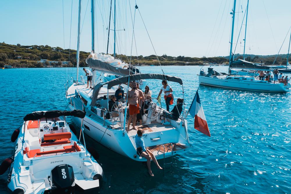 Voilier au mouillage dans une crique aux eaux turquoise, l'équipage à bord