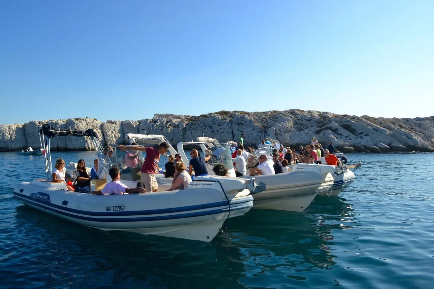 Semi-rigides amarrés bord à bord devant une île, pendant l'escale d'un rallye nautique