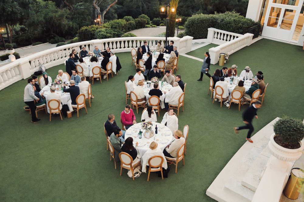 Terrasse d'une demeure avec ses tables rondes pleines d'invités, vue d'en haut
