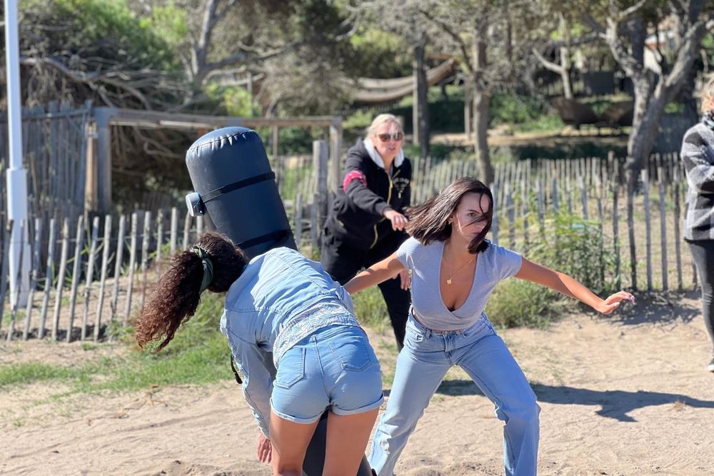 Duel à deux sur le sable, sous les pins, encouragé par les équipes
