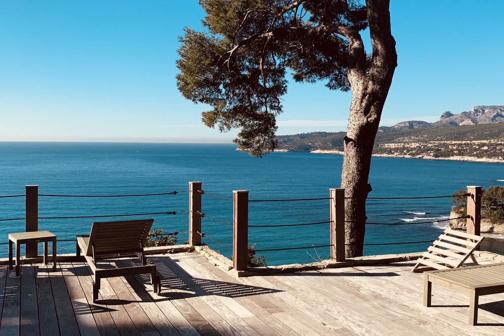 Terrasse en bois face à la mer, à l'ombre d'un pin