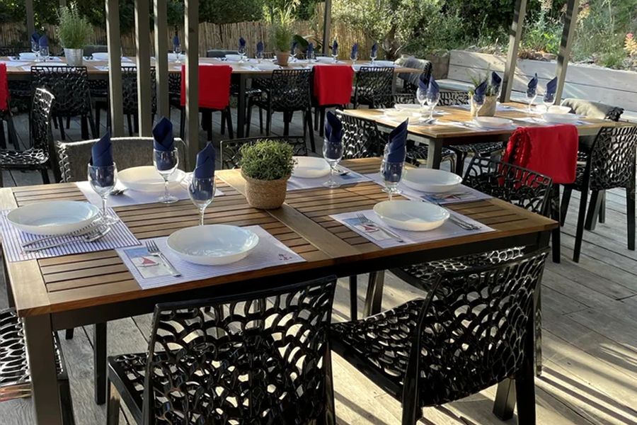 Tables dressées sous la pergola d'un cabanon, face à la calanque