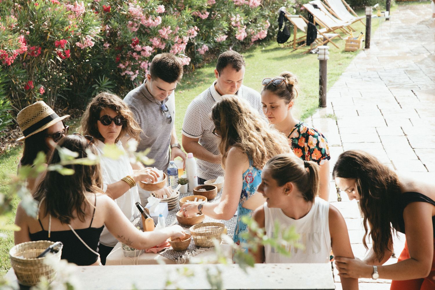 Participants d'un atelier réunis debout autour d'une grande table, dans un jardin fleuri