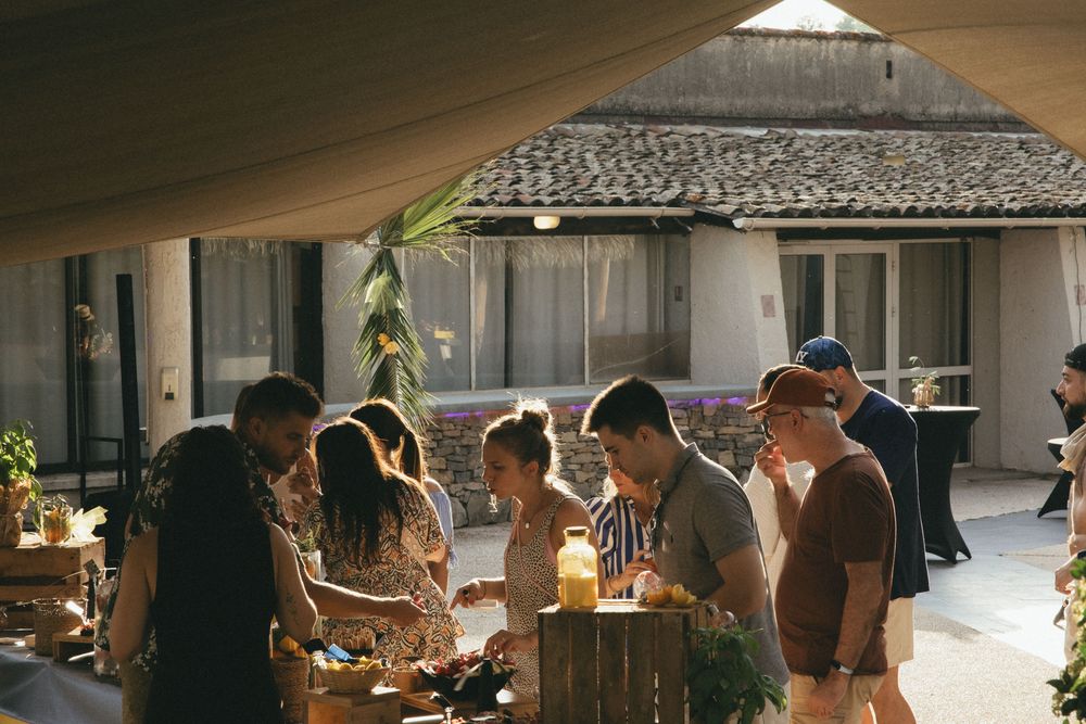 Participants autour d'une table sous une toile tendue, devant un mas