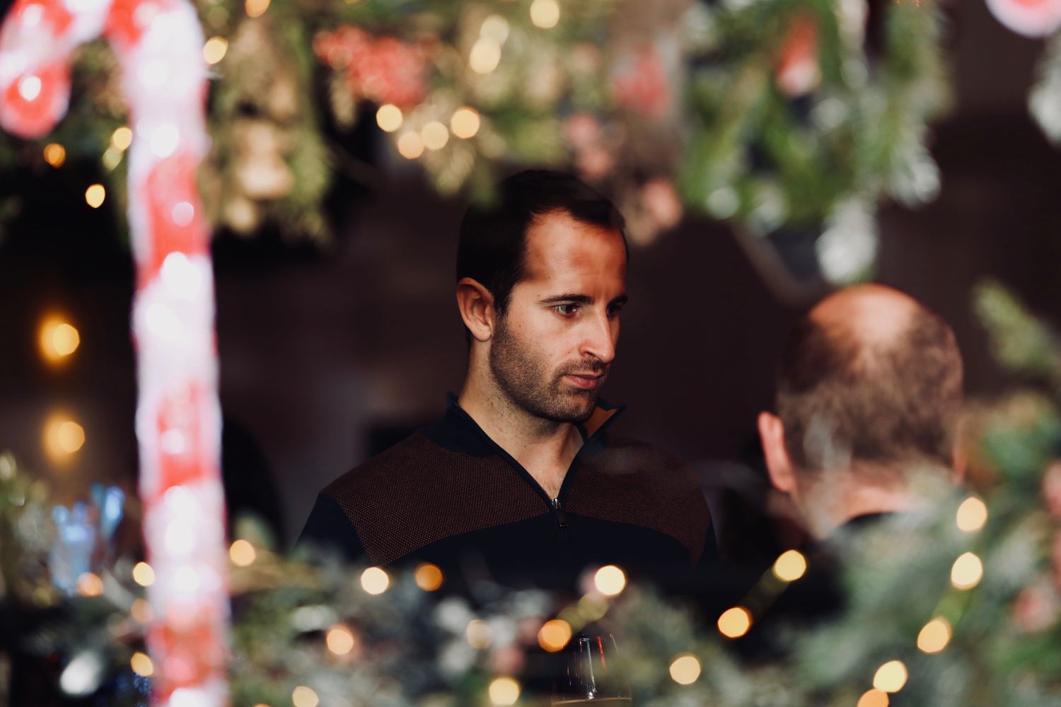 Invité sous les branches d'un sapin décoré et les sucres d'orge géants d'un arbre de Noël d'entreprise