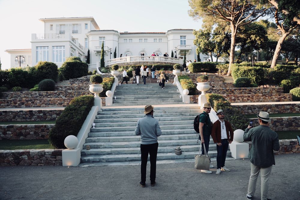 Invités qui montent le grand escalier d'une demeure au milieu des pins