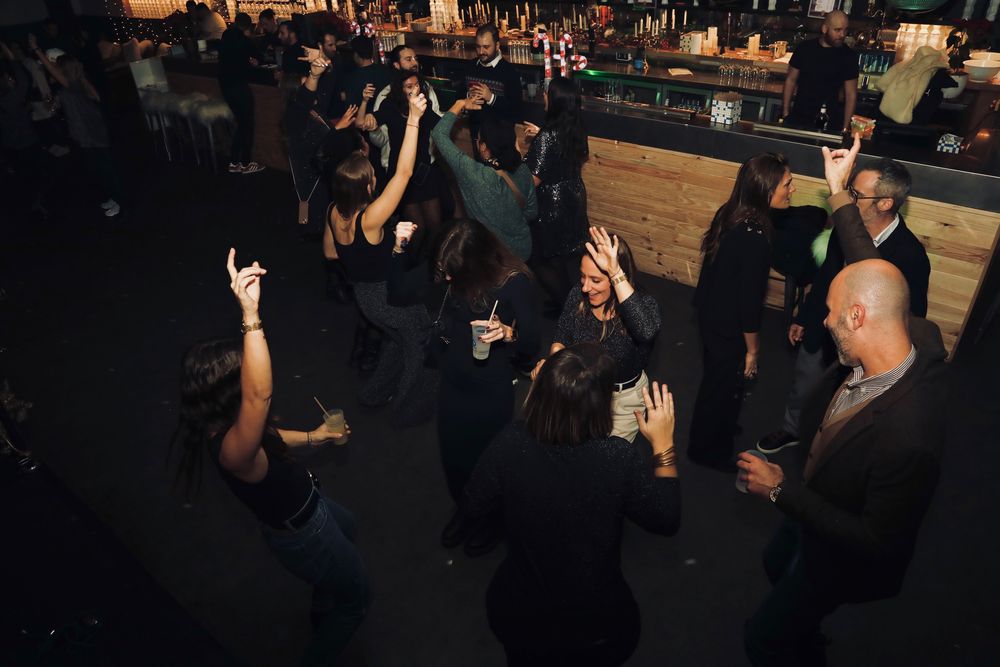 Piste de danse pleine, les bras en l'air, sous les lumières de la salle