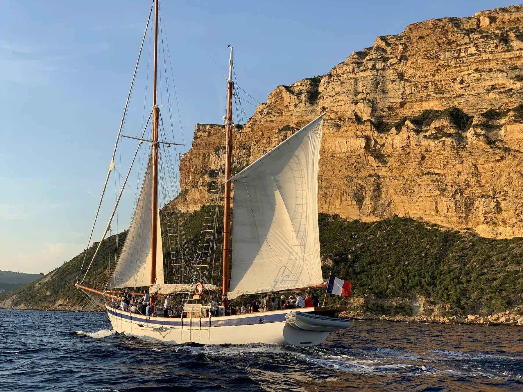 Vieux gréement sous voiles au pied des falaises
