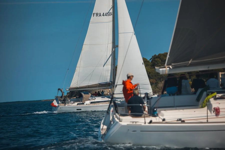 Voilier barré par un participant le long de la côte