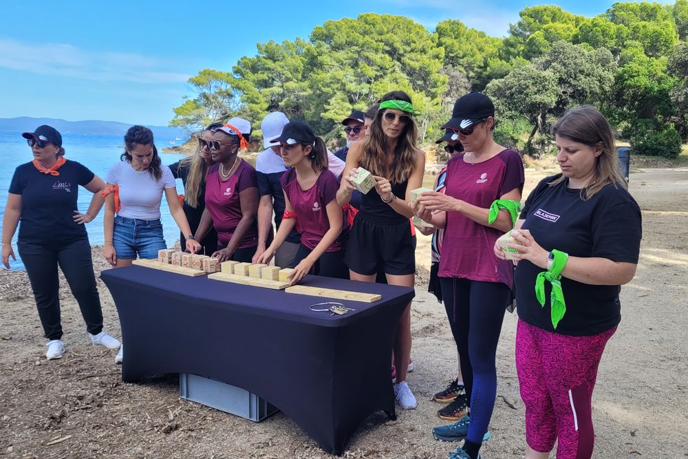 Équipe réunie autour d'un défi de construction, sur une plage face à la mer