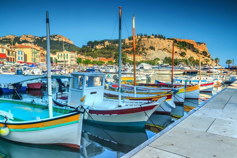 Pointus colorés le long du quai, façades et falaises en fond