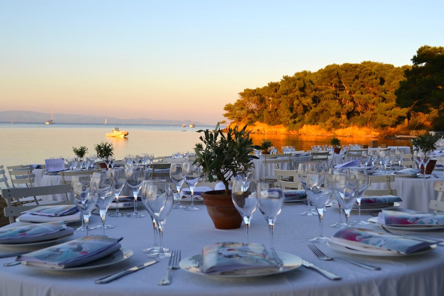 Table de gala dressée face à la mer, l'île en face éclairée par le soleil couchant