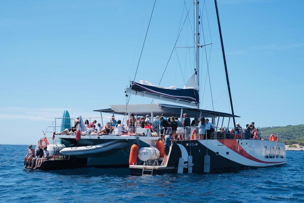 Maxi-catamaran au mouillage, les invités se baignant depuis l'arrière