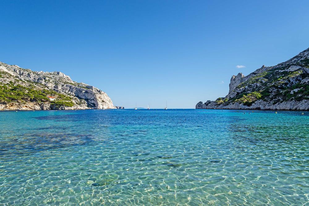 Eau turquoise d'une calanque entre deux falaises blanches