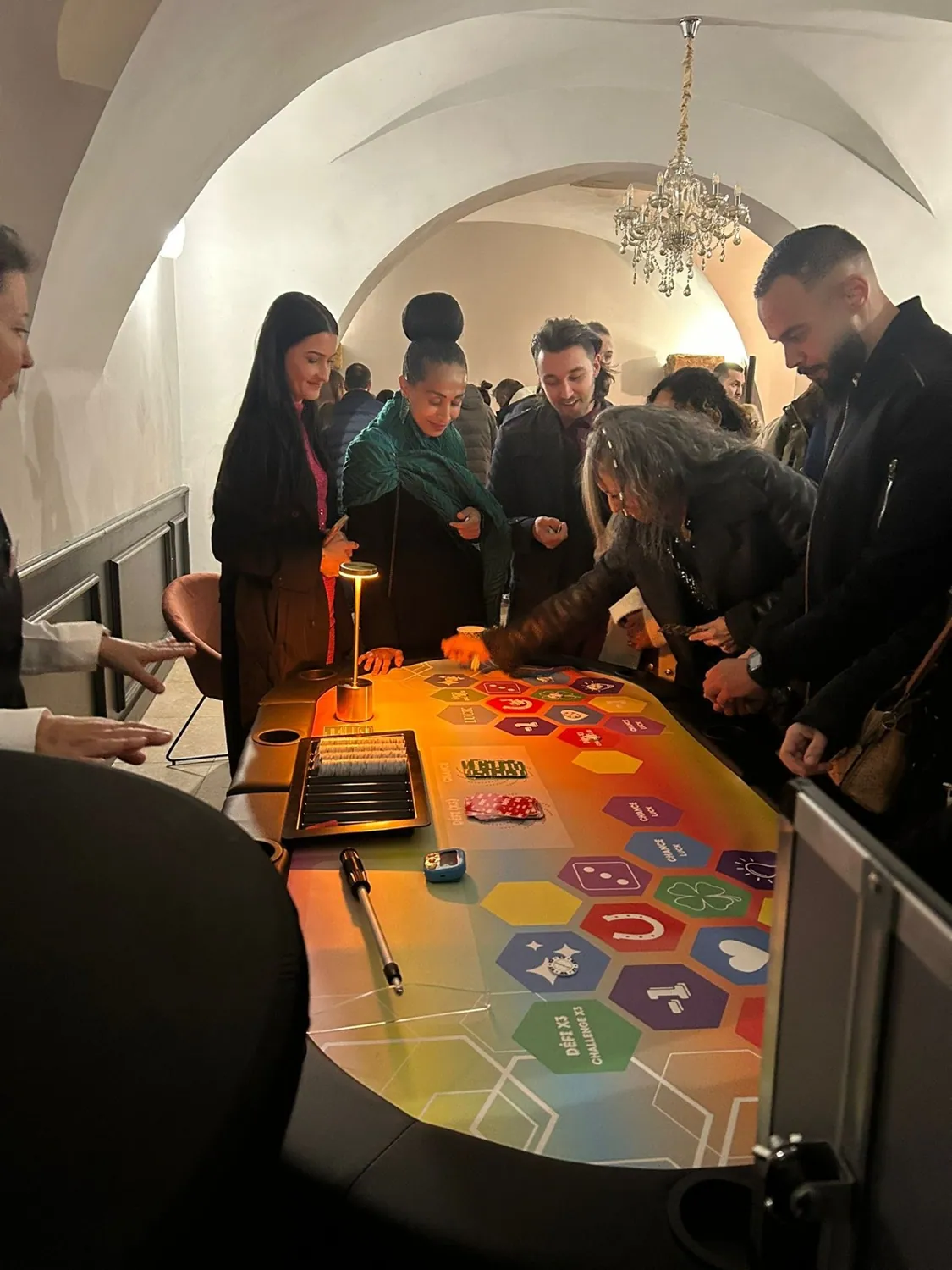Tables de casino éclairées installées dans une salle voûtée, joueurs autour