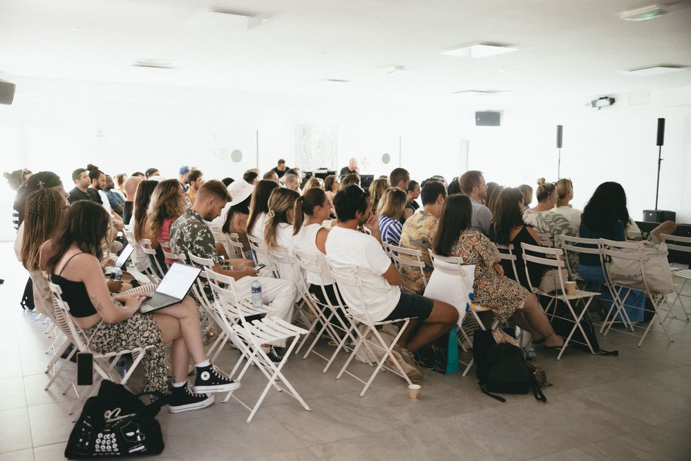 Participants assis en rangs dans une salle lumineuse, ordinateurs sur les genoux