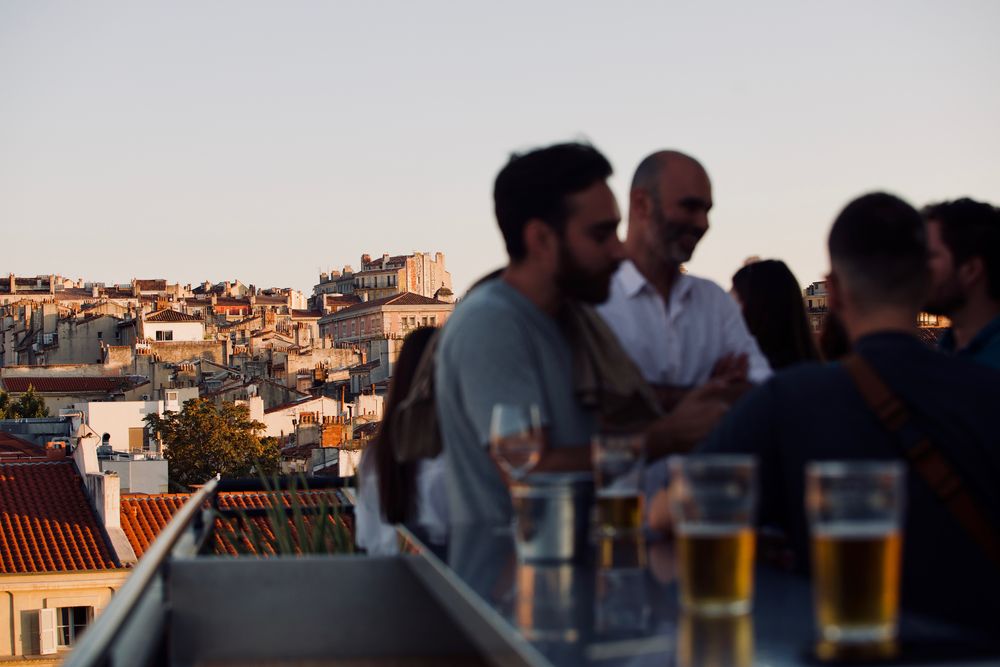 Collègues autour d'une table haute, des bières face aux toits