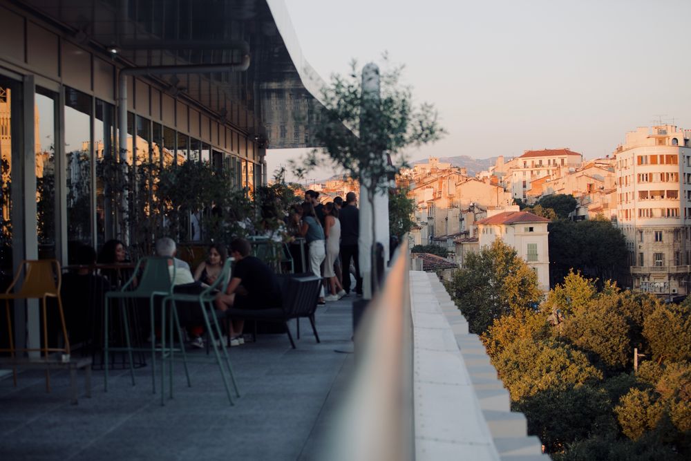 Terrasse d'un rooftop au-dessus des toits, à l'heure dorée