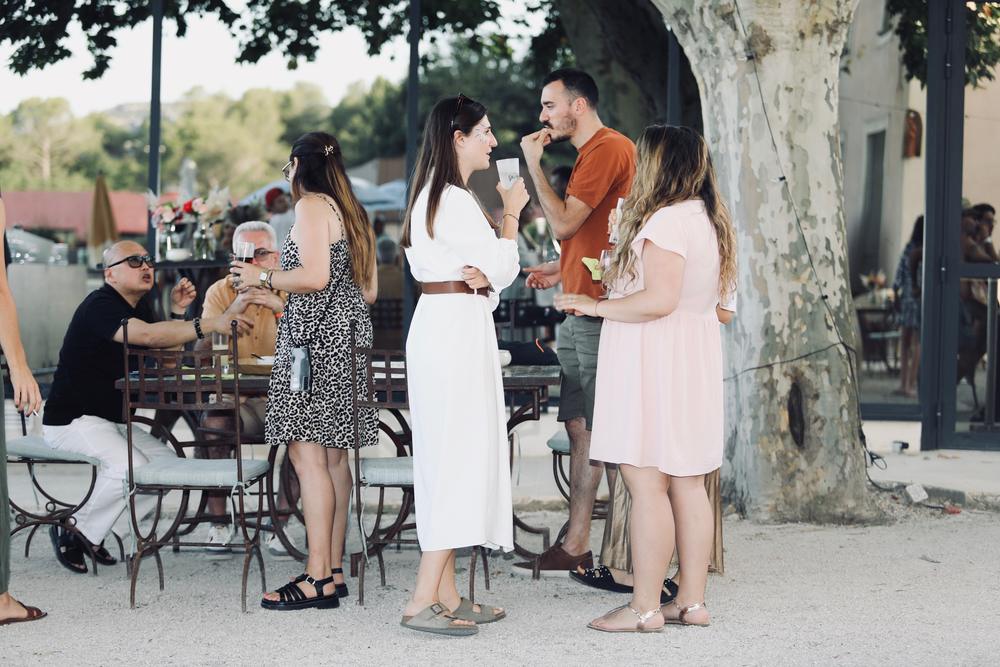 Participants d'un kick-off discutant à l'ombre des platanes pendant l'apéritif