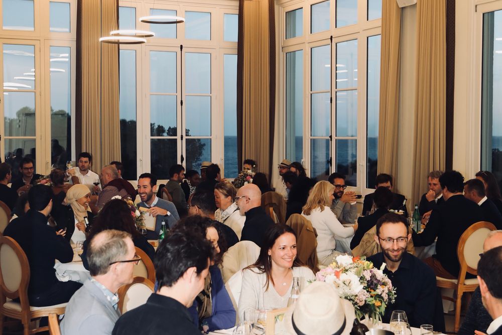 Salle de réception pleine pendant le dîner, devant de grandes baies vitrées