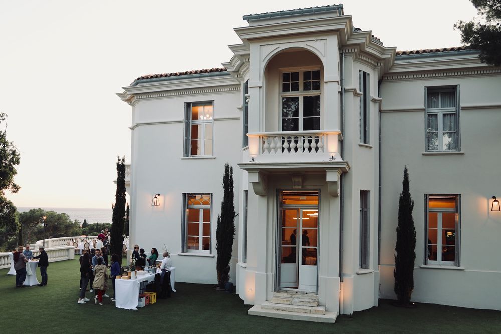 Invités réunis au pied d'une villa blanche, avant la soirée