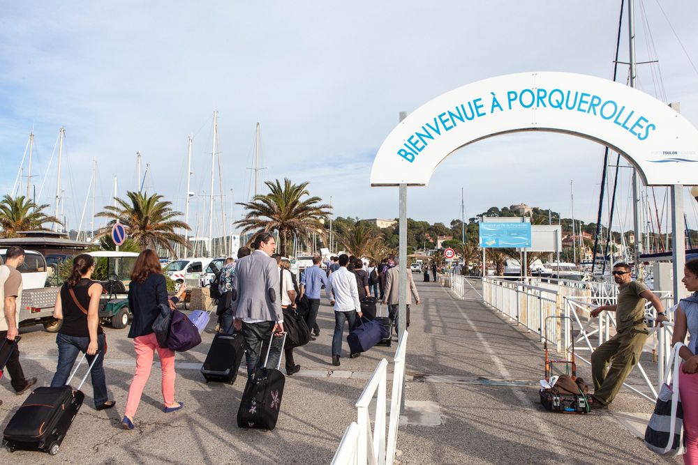 Arrivée d'un groupe à Porquerolles, valises à la main, sous l'arche de bienvenue