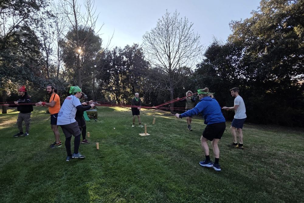 Équipes reliées par des cordes autour d'un jeu en bois, sur une pelouse