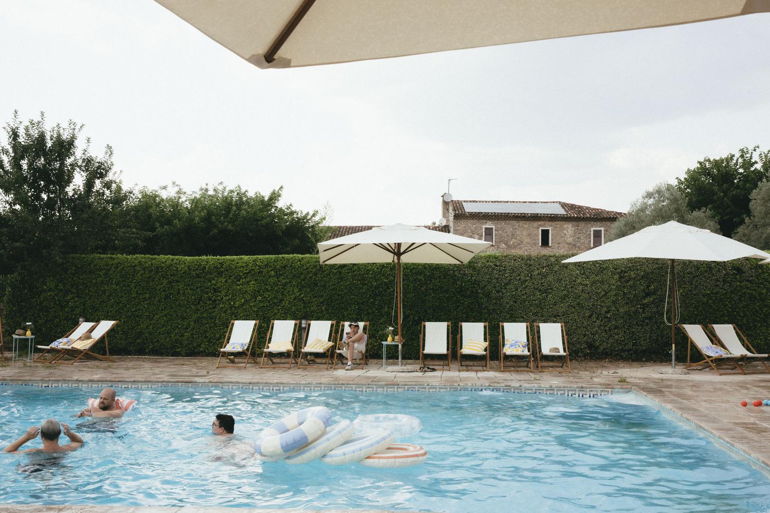 Piscine d'un domaine provençal privatisé pour un offsite, parasols et bastide en fond
