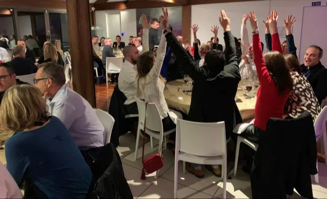Les tables d'un dîner, bras levés pendant une manche du quiz