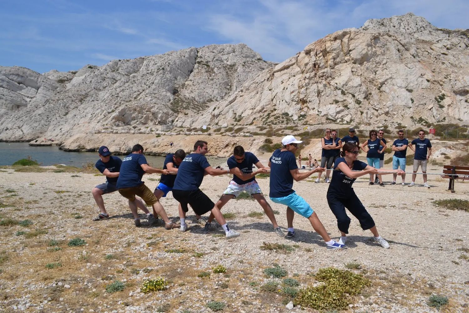 Tir à la corde entre collègues au pied des falaises blanches des Calanques