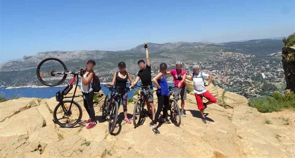 Une équipe et ses vélos électriques sur une crête, la baie de Cassis en contrebas