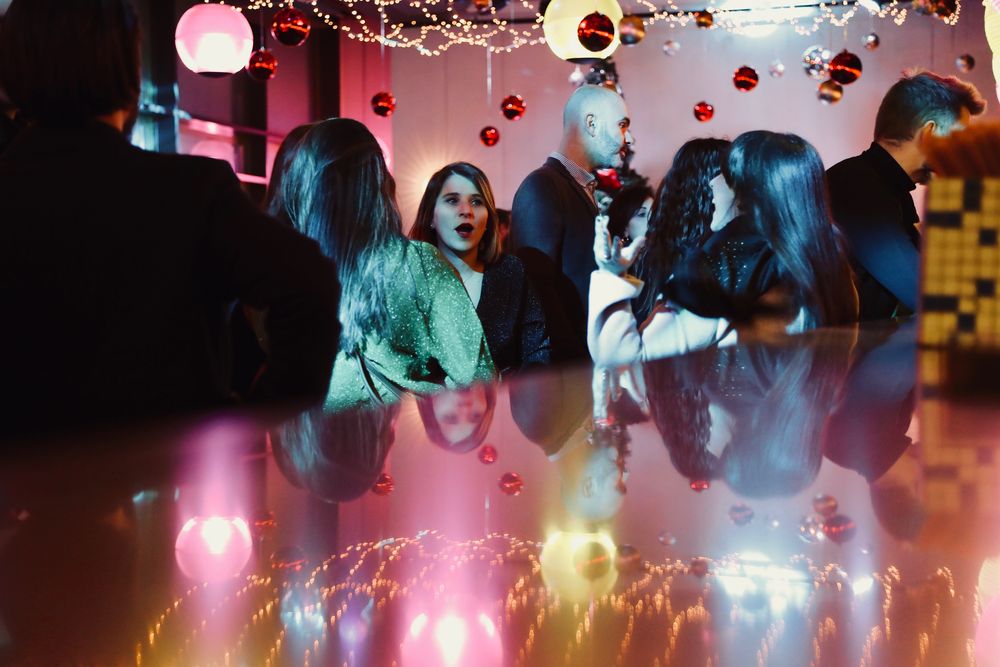 Invités au bar sous les boules de Noël et les lumières roses d'une salle privatisée