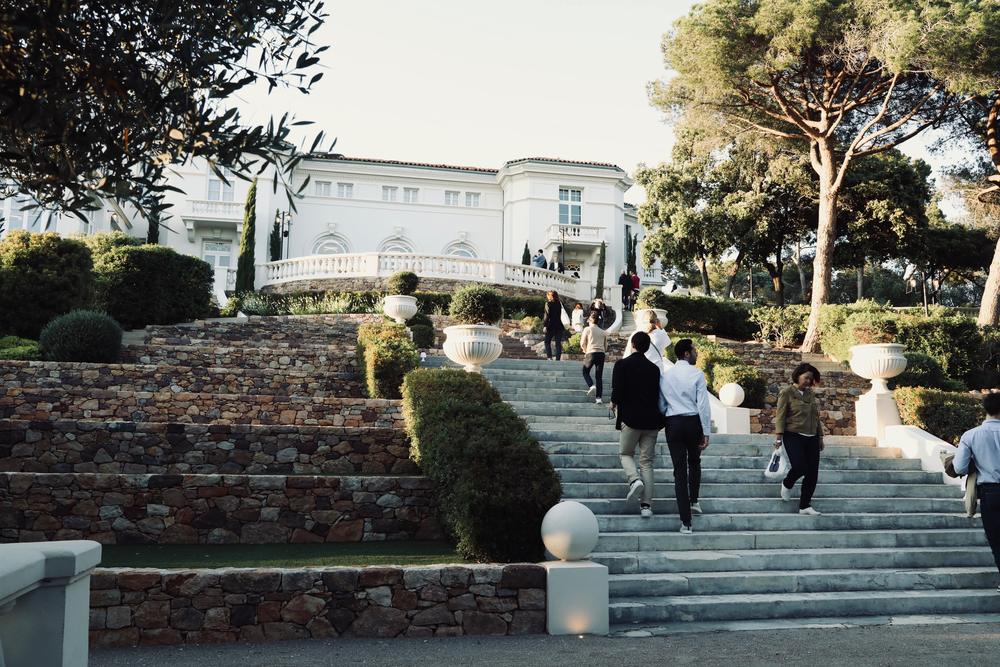Participants montant l'escalier d'une villa blanche entre les pins