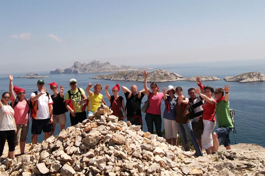 Groupe de randonneurs, bras levés, face à la mer