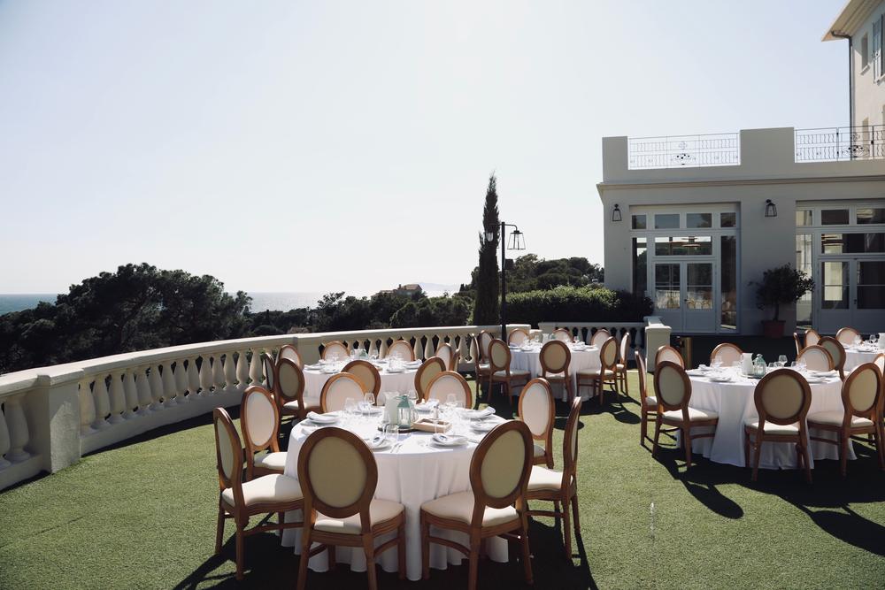 Tables dressées sur la terrasse d'une villa, la mer en contrebas
